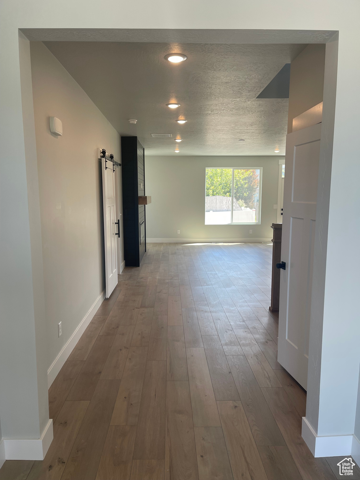 Hall featuring a textured ceiling, dark wood-type flooring, and a barn door