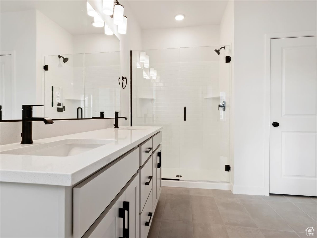 Bathroom featuring vanity with extensive cabinet space, tile floors, and a shower with shower door