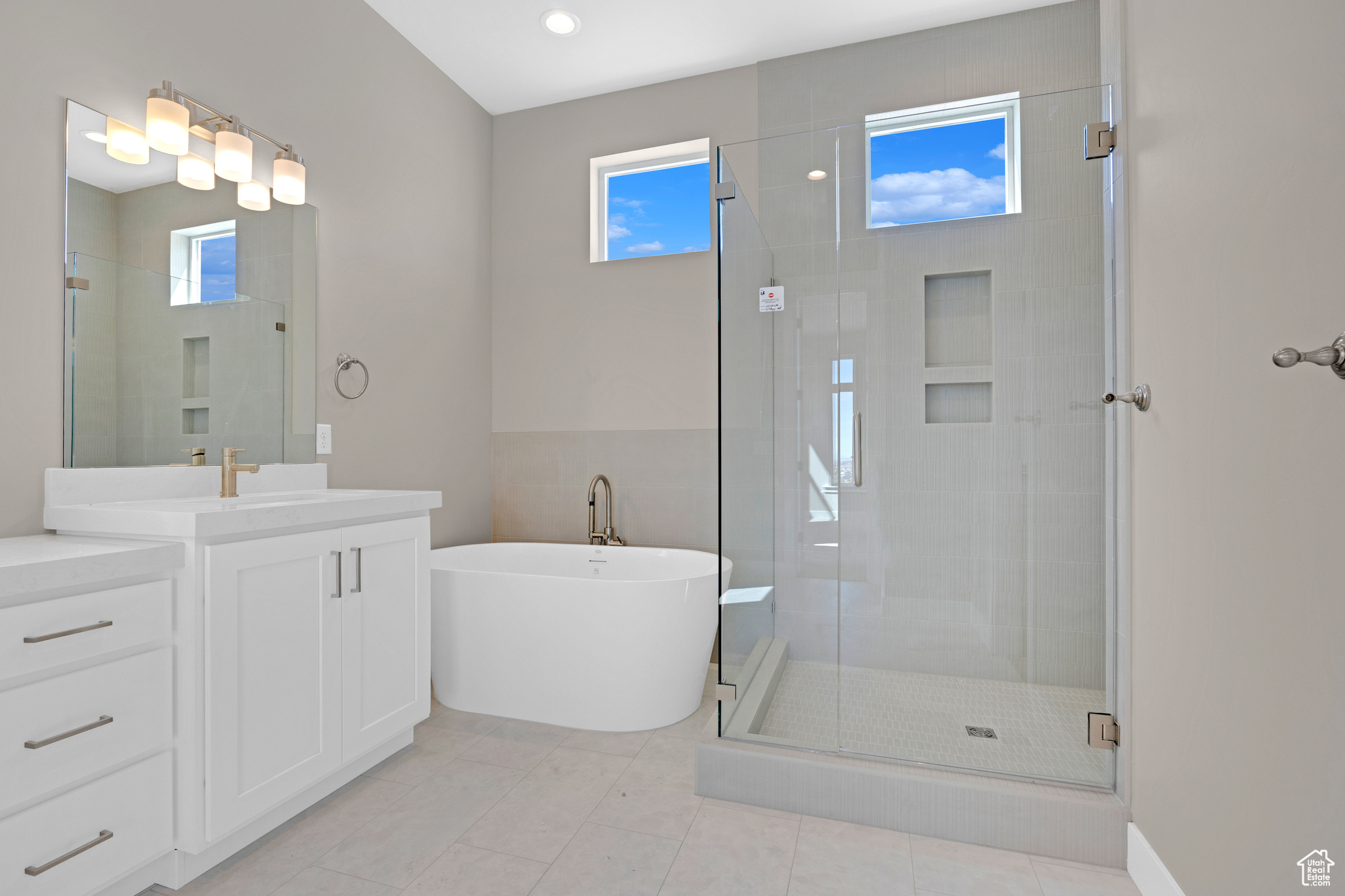 Bathroom with a healthy amount of sunlight, an enclosed shower, tile floors, and vanity