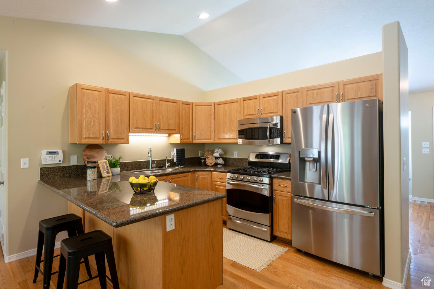 Kitchen featuring kitchen peninsula, stainless steel appliances, sink, light wood flooring, and a breakfast bar