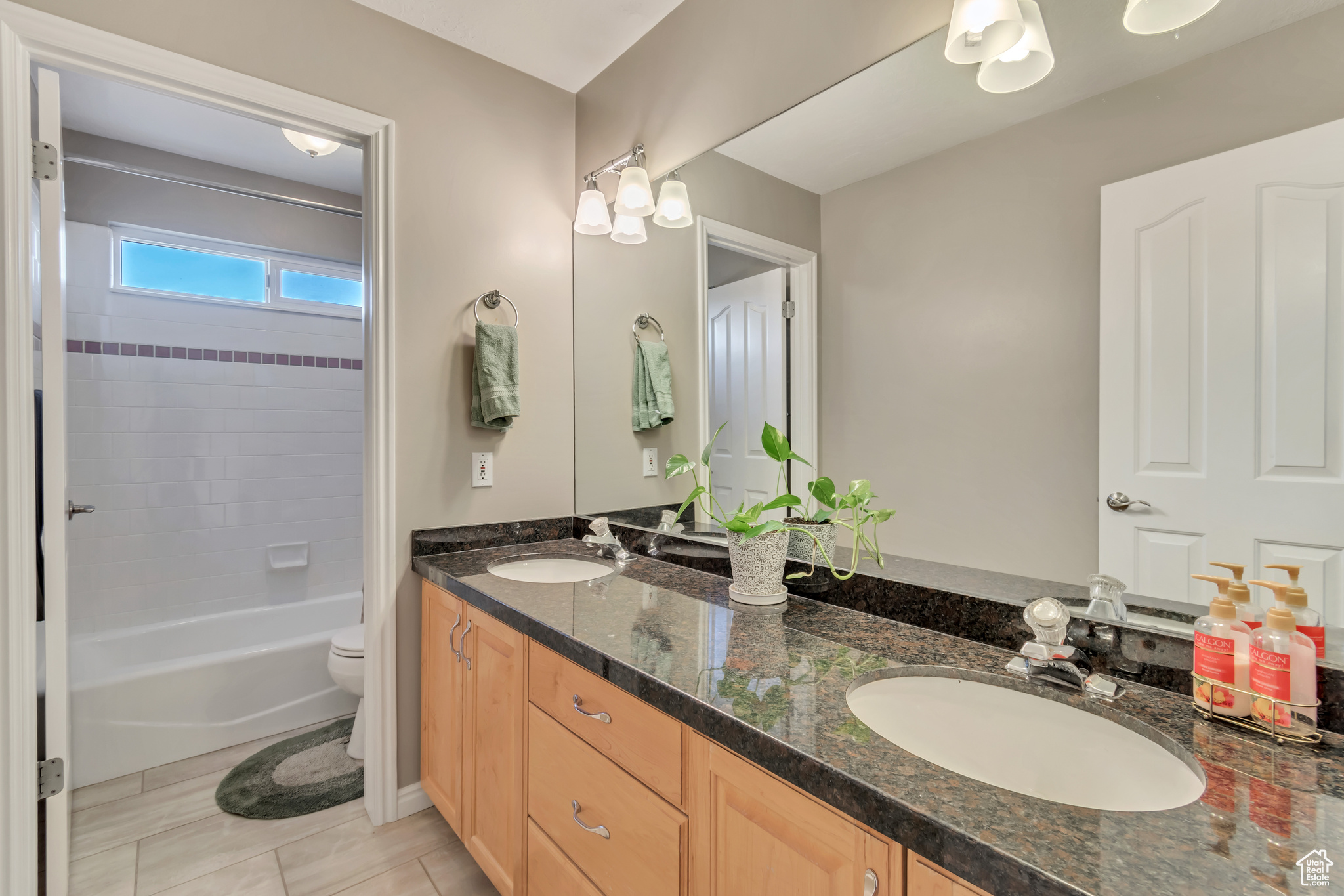 Full bathroom featuring double vanity, tiled shower / bath, toilet, and tile floors