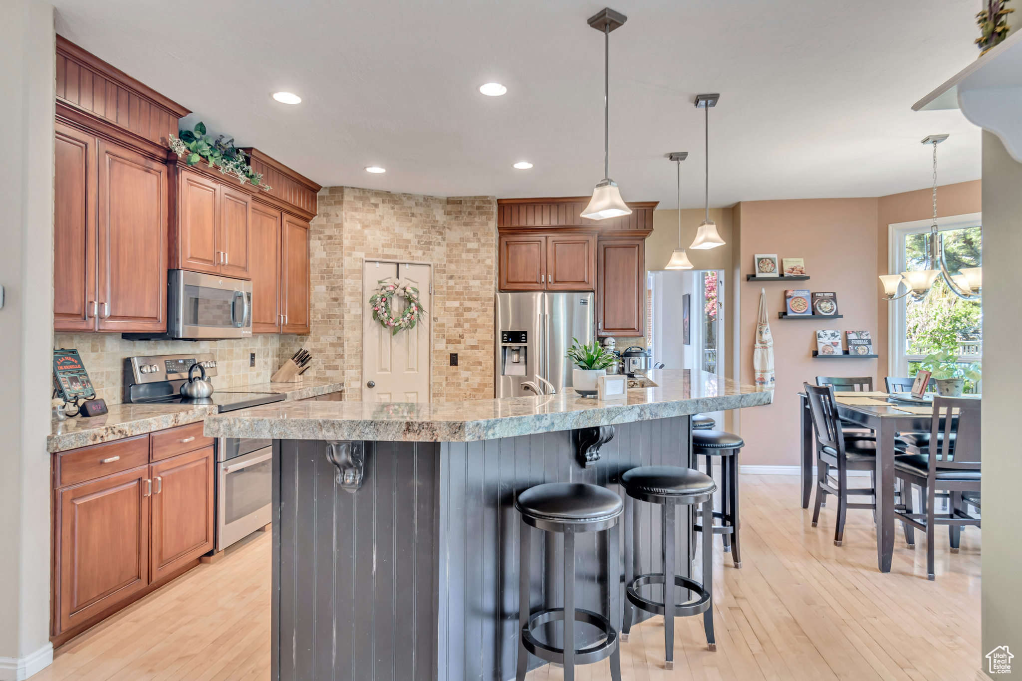 Kitchen with pendant lighting, appliances with stainless steel finishes, light hardwood / wood-style flooring, and a breakfast bar area