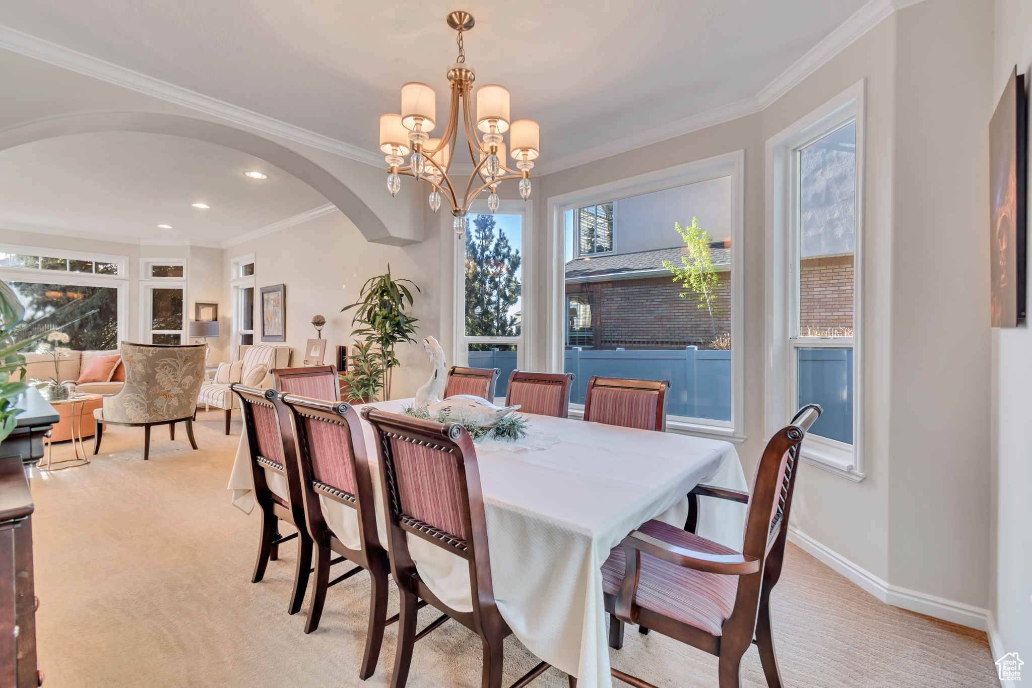 Dining area with light colored carpet, plenty of natural light, an inviting chandelier, and ornamental molding