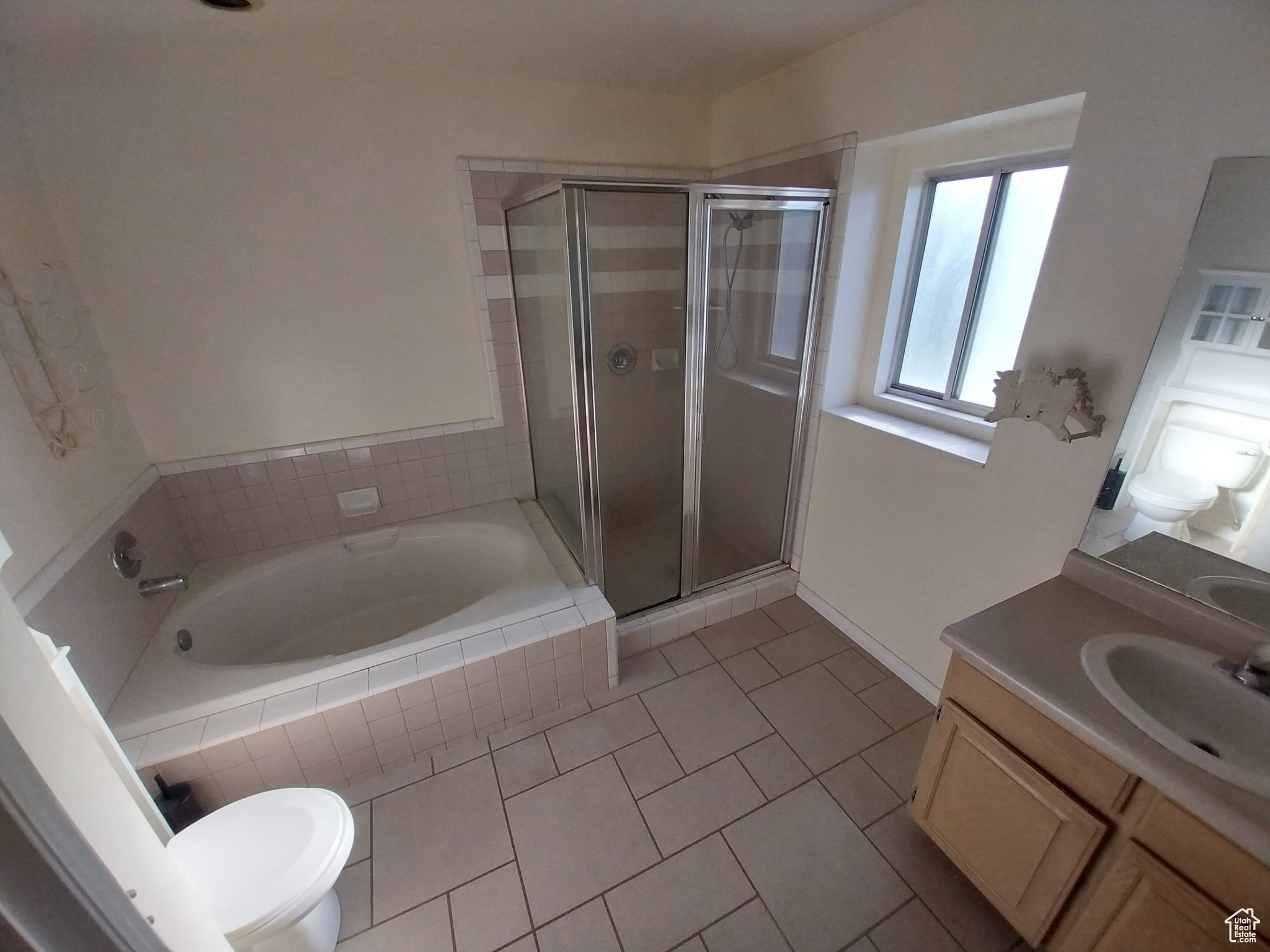 Full bathroom featuring shower with separate bathtub, toilet, tile floors, and vanity