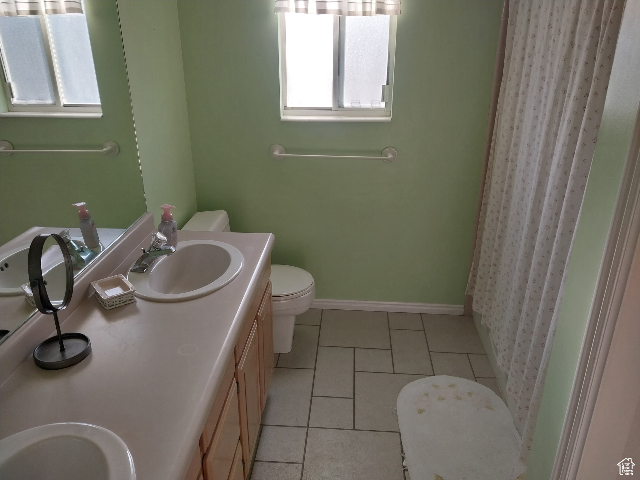 Bathroom featuring toilet, tile floors, and dual bowl vanity