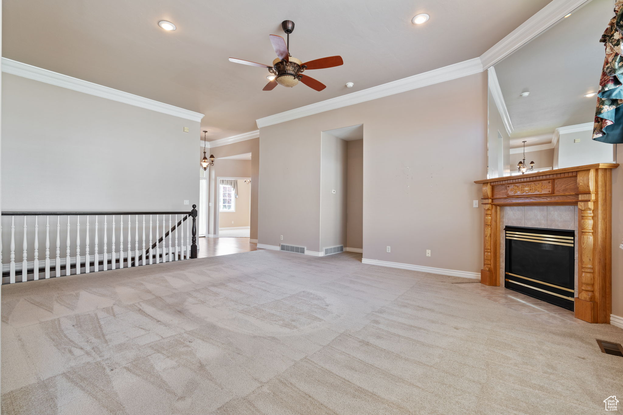 Unfurnished living room with ceiling fan, crown molding, a tile fireplace, and carpet floors