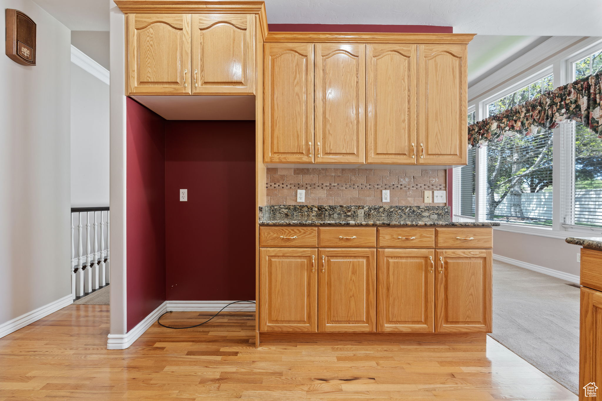 Kitchen featuring light colored carpet, plenty of natural light, tasteful backsplash, and dark stone countertops