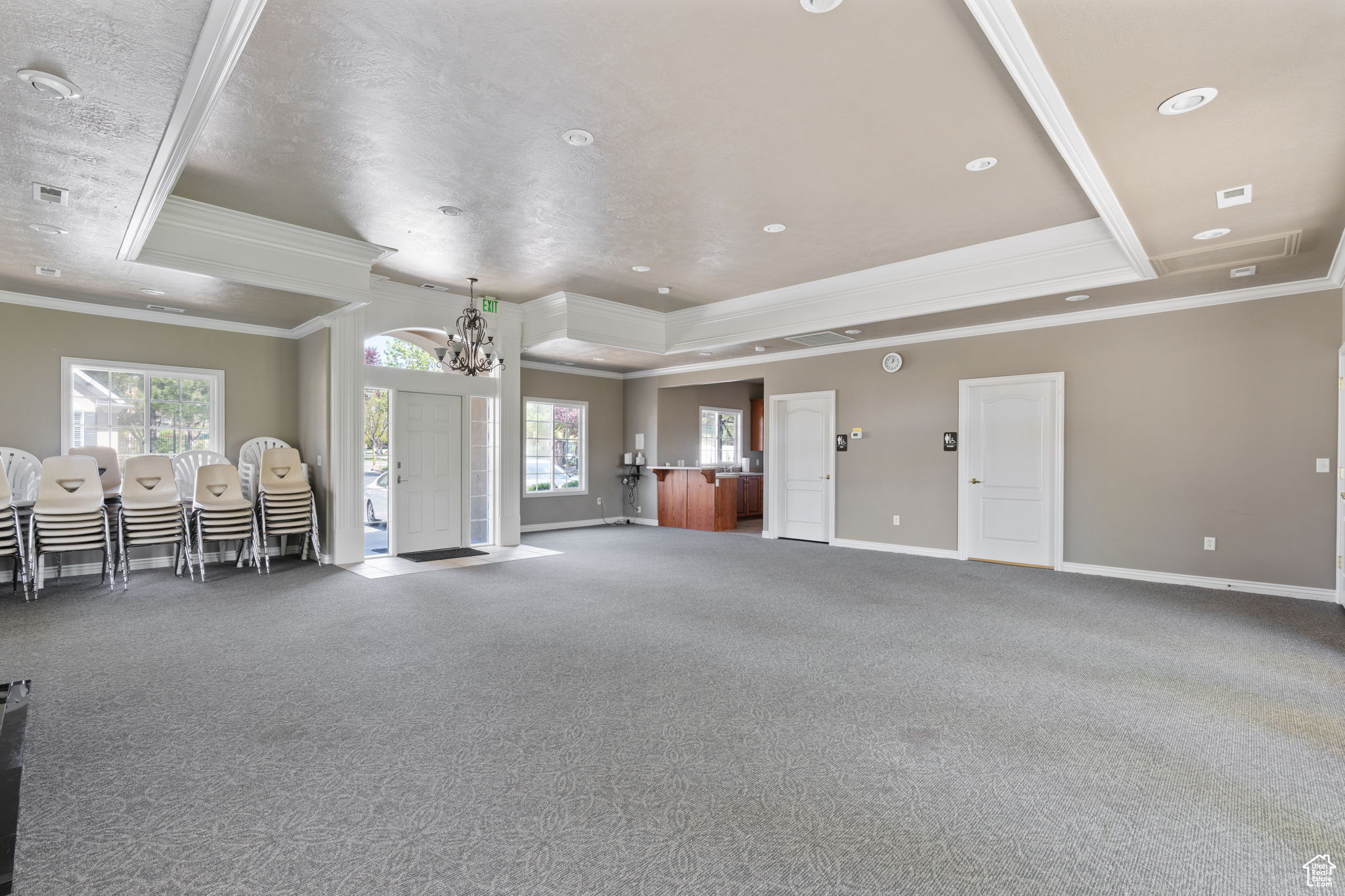 Clubhouse  meeting room featuring crown molding, carpet, a notable chandelier, and a tray ceiling
