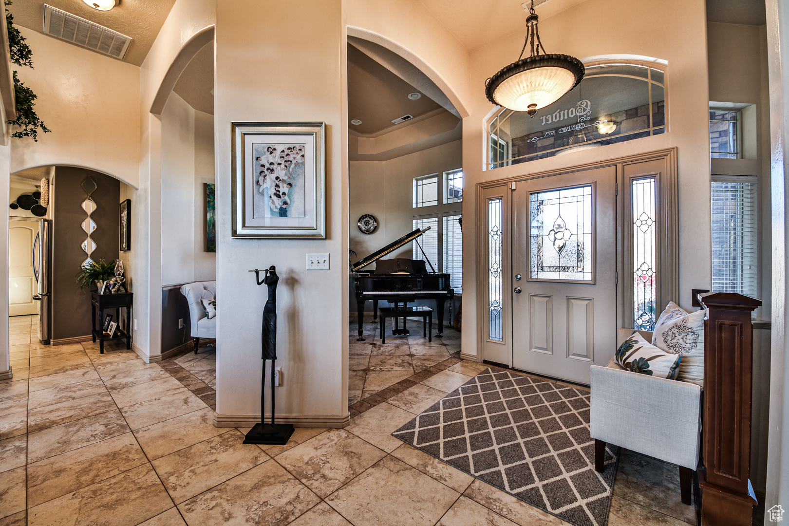 Tiled entryway featuring a towering ceiling and a tray ceiling