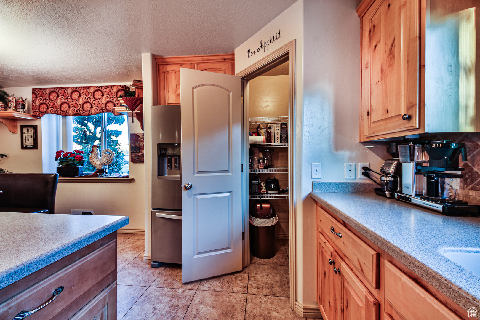 Kitchen with a textured ceiling, light tile floors, and stainless steel refrigerator with ice dispenser