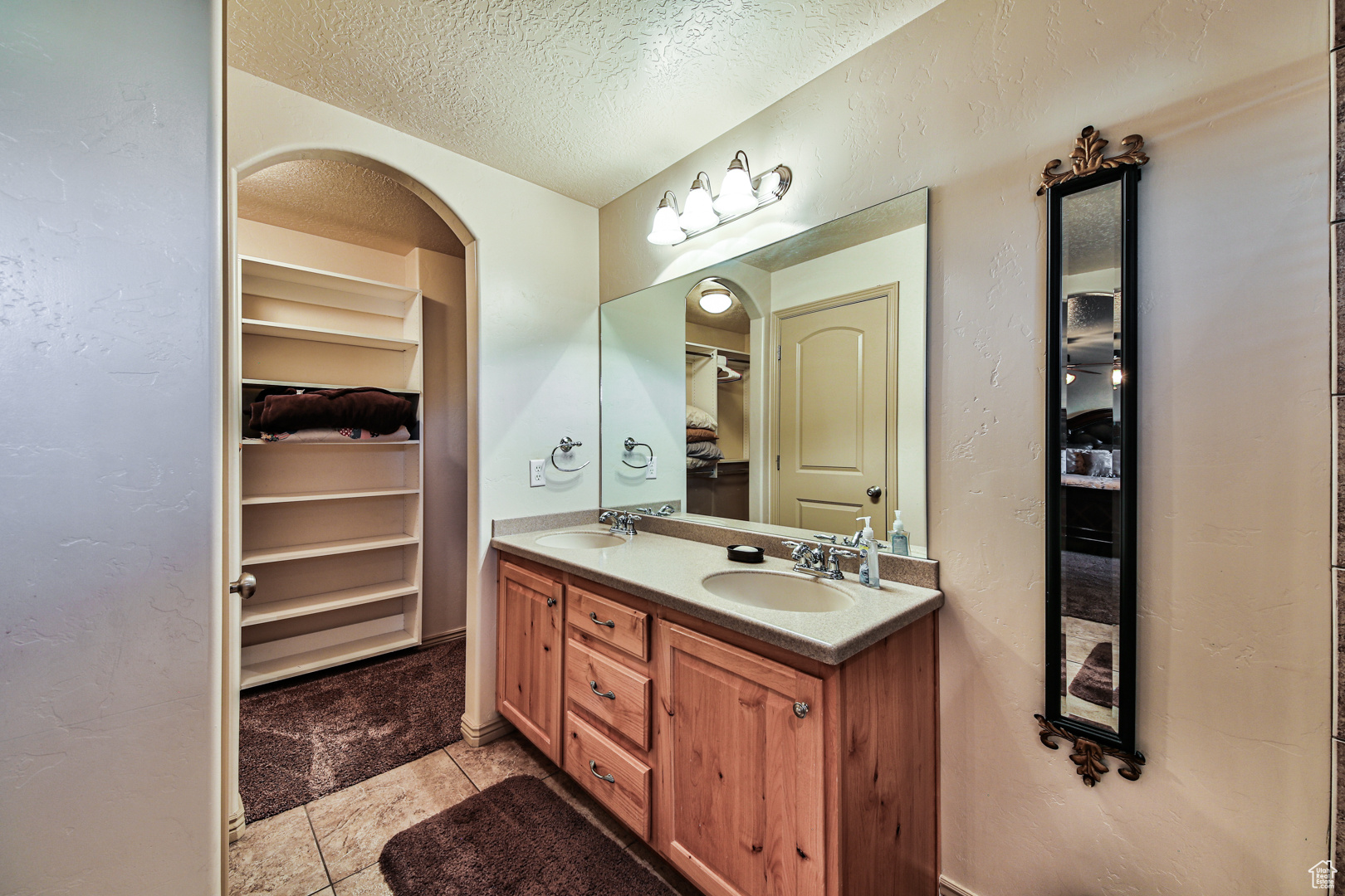 Bathroom with dual bowl vanity, tile floors, and a textured ceiling