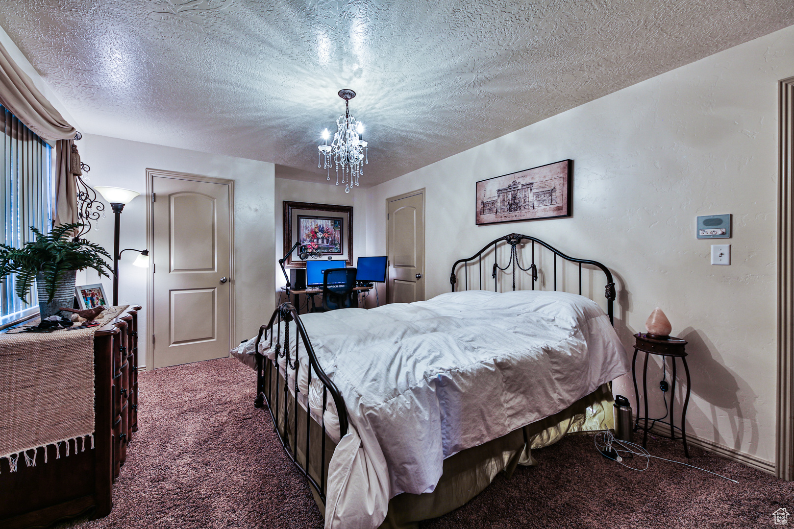 Carpeted bedroom featuring an inviting chandelier and a textured ceiling