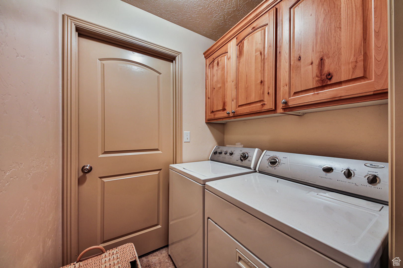 Laundry room with cabinets, separate washer and dryer, and a textured ceiling