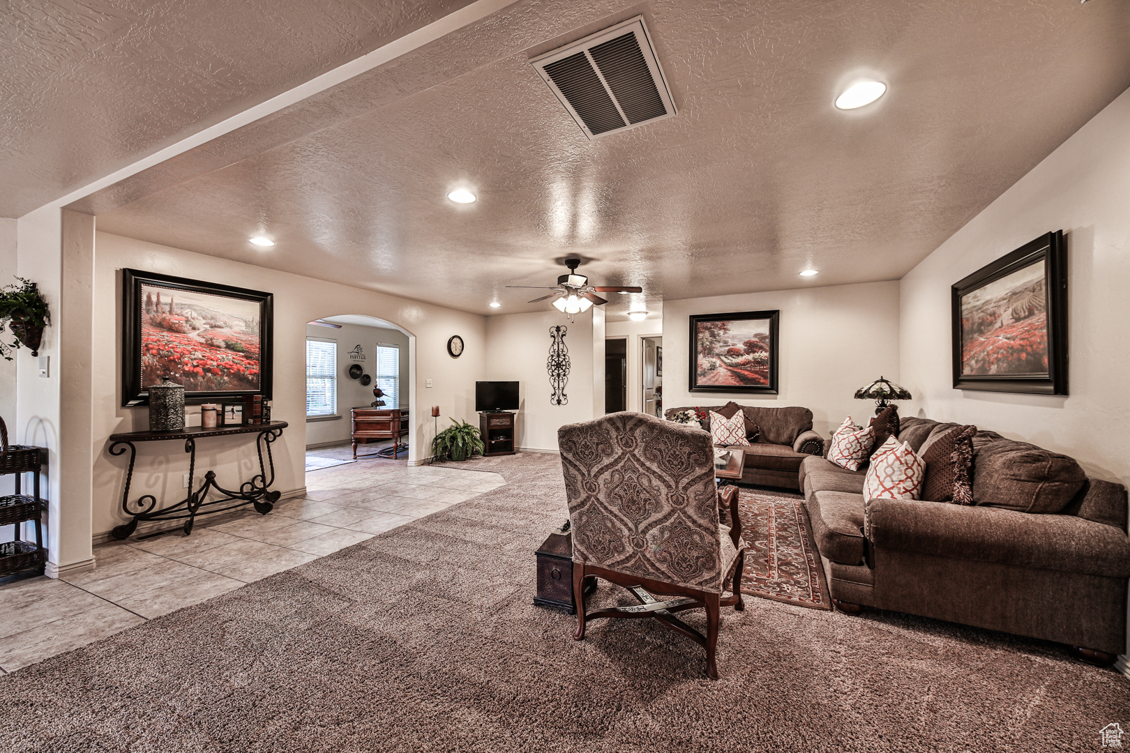 Tiled living room with ceiling fan and a textured ceiling