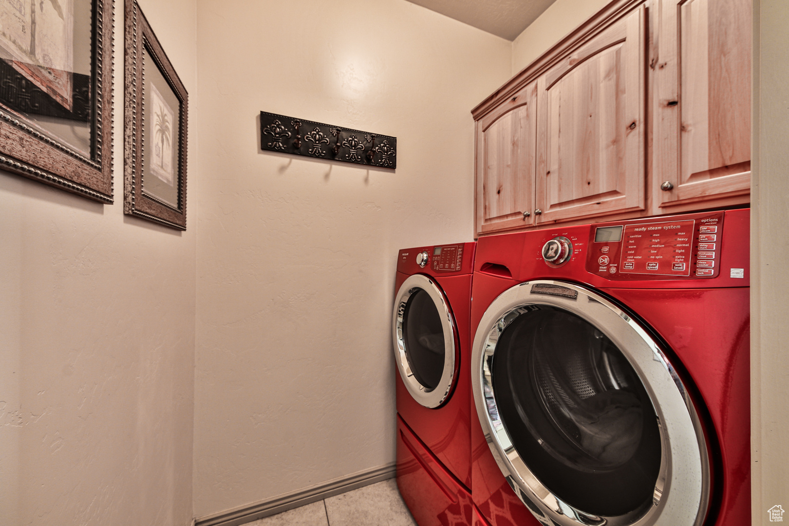 Laundry area featuring cabinets, washing machine and dryer, and light tile floors