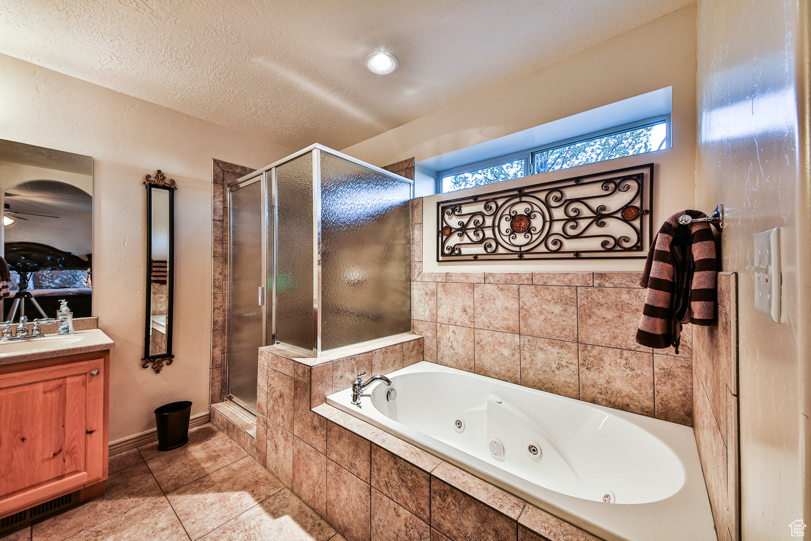 Bathroom with tile flooring, independent shower and bath, vanity, and a textured ceiling