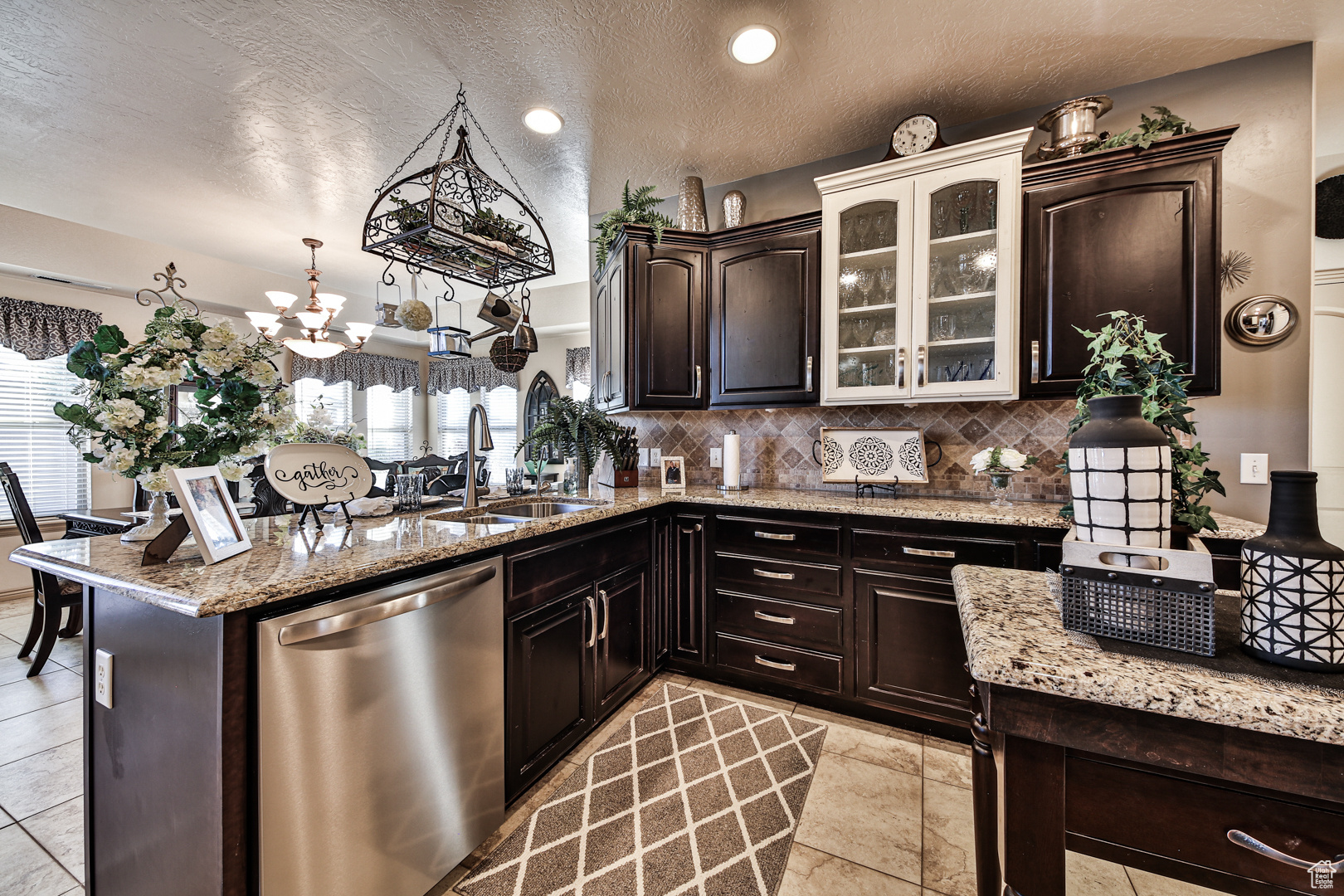 Kitchen featuring light tile flooring, dishwasher, a textured ceiling, tasteful backsplash, and sink