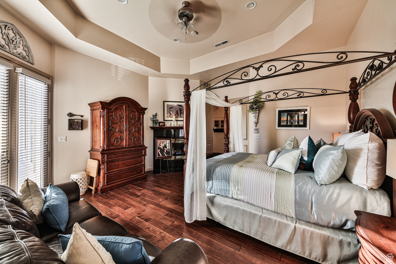 Bedroom with wood-type flooring, ceiling fan, and a tray ceiling