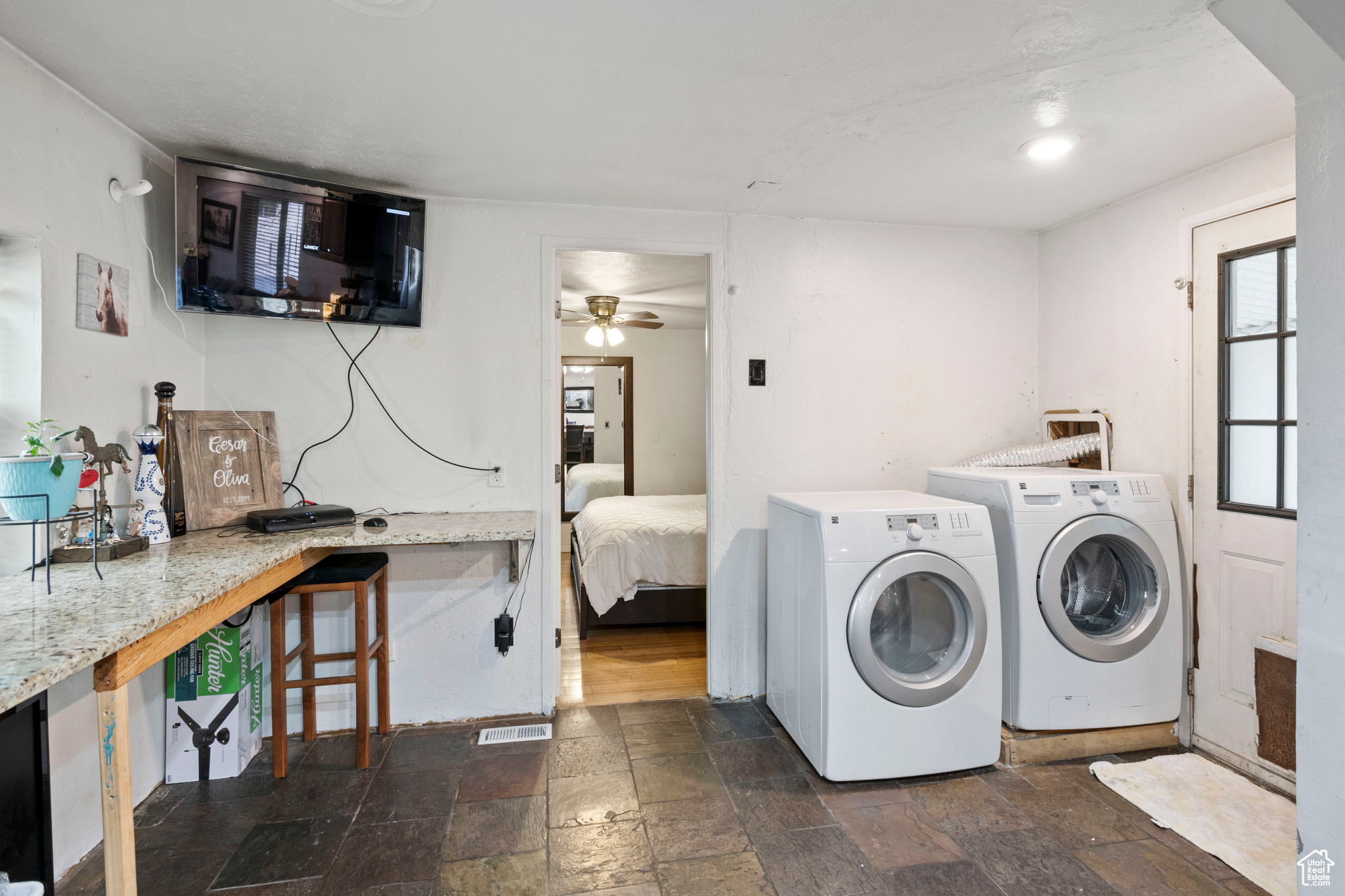Laundry area featuring dark tile flooring, ceiling fan, and washer and dryer