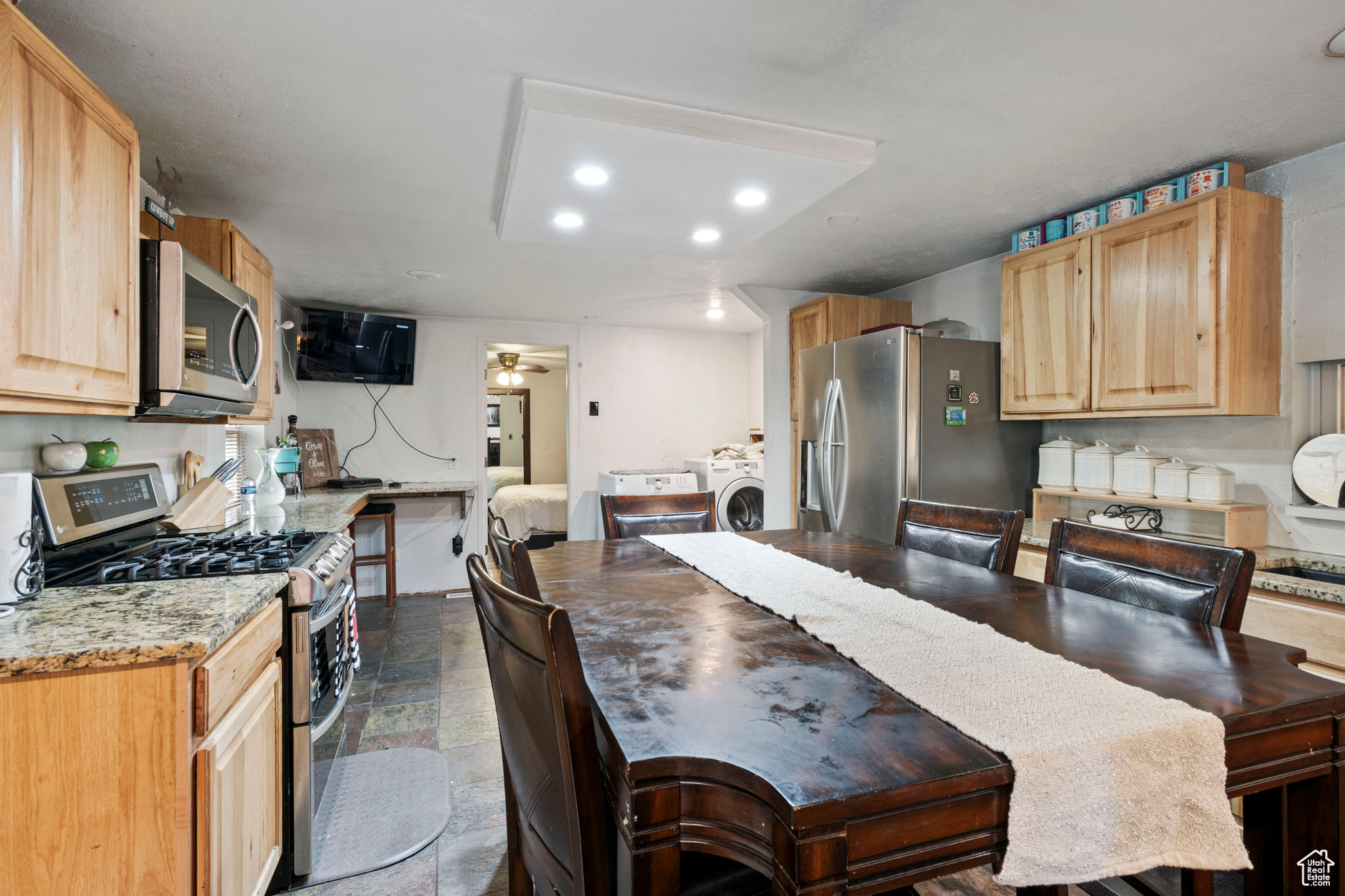 Kitchen with washer / clothes dryer, light brown cabinetry, stainless steel appliances, tile flooring, and ceiling fan