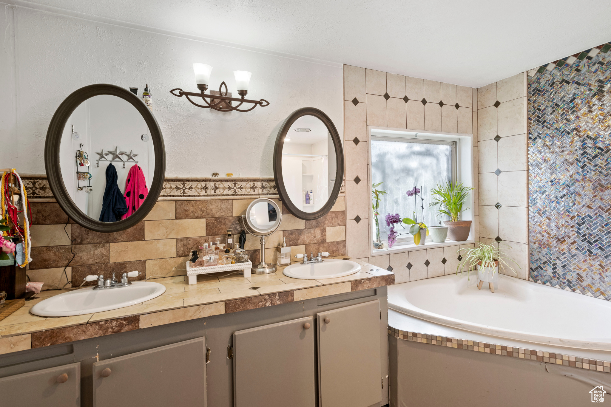 Bathroom featuring tasteful backsplash, tile walls, dual bowl vanity, and a tub