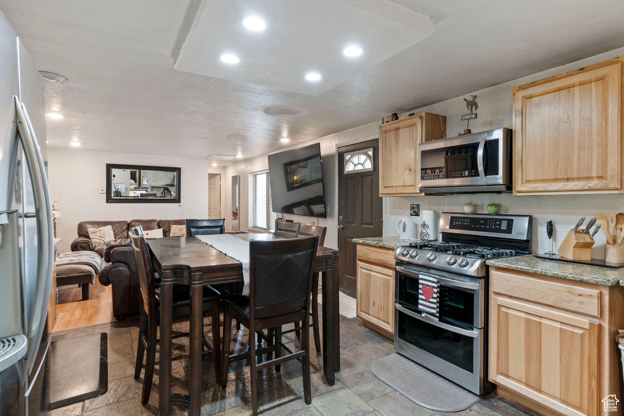 Kitchen with light brown cabinets, stainless steel appliances, light stone counters, and tile flooring