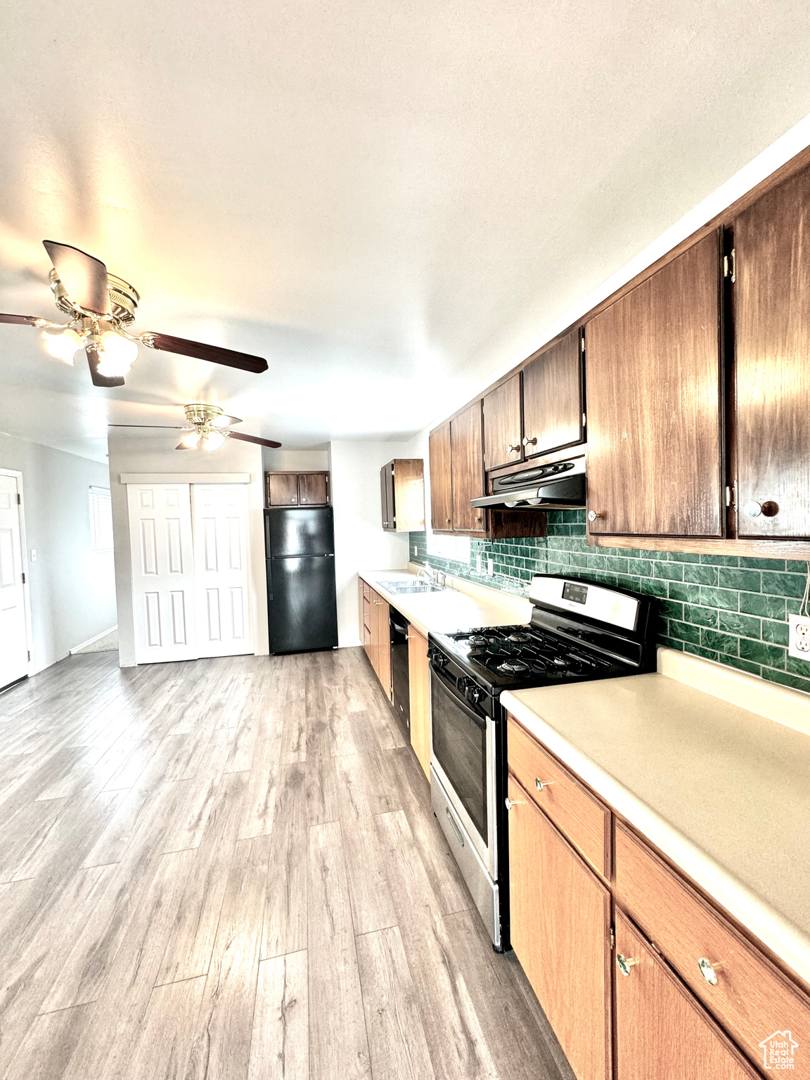Kitchen featuring ceiling fan, sink, light hardwood / wood-style floors, tasteful backsplash, and black appliances