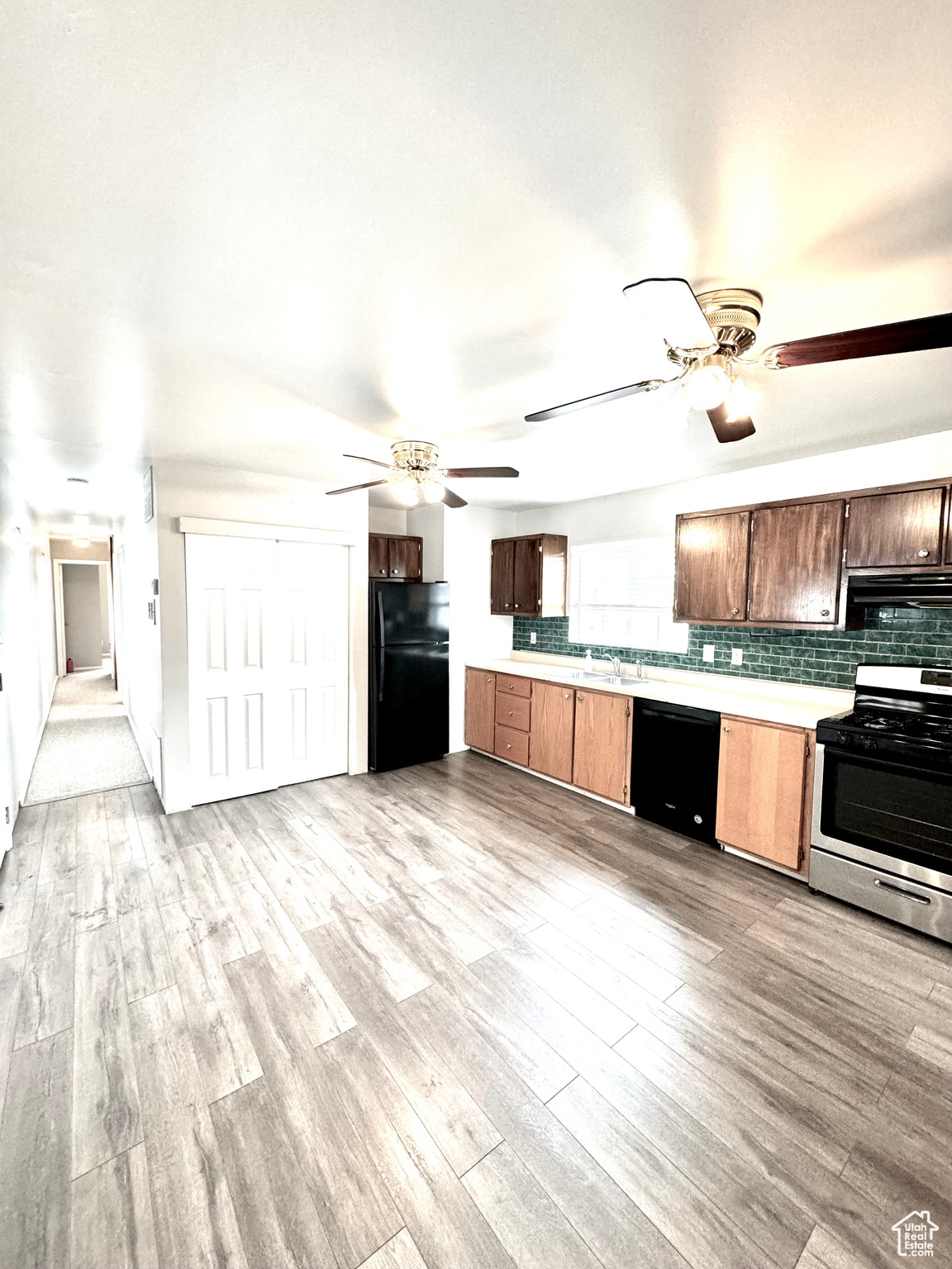 Kitchen with range hood, ceiling fan, light wood-type flooring, and black appliances
