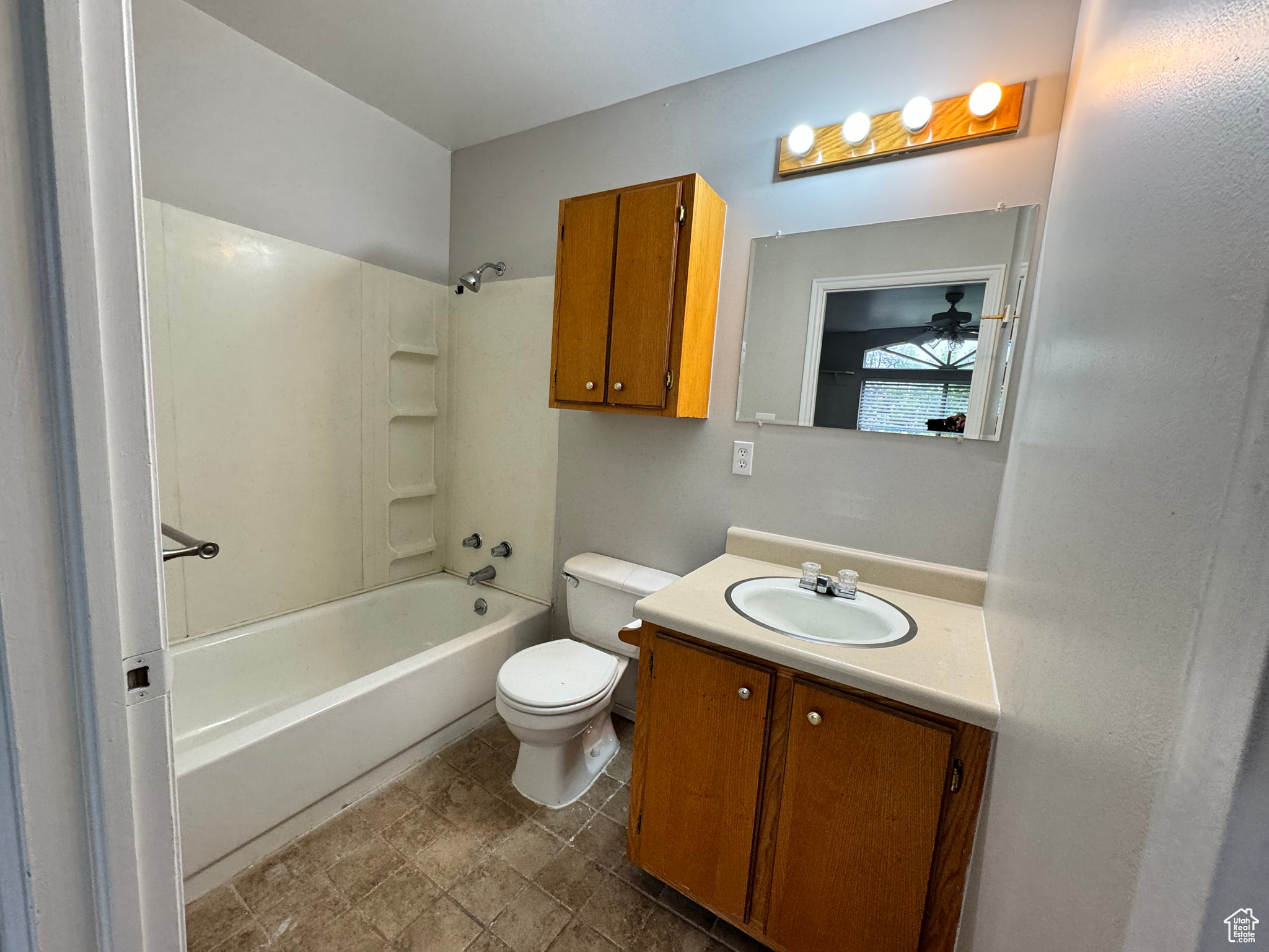 Full bathroom with ceiling fan, toilet, vanity, tub / shower combination, and tile floors