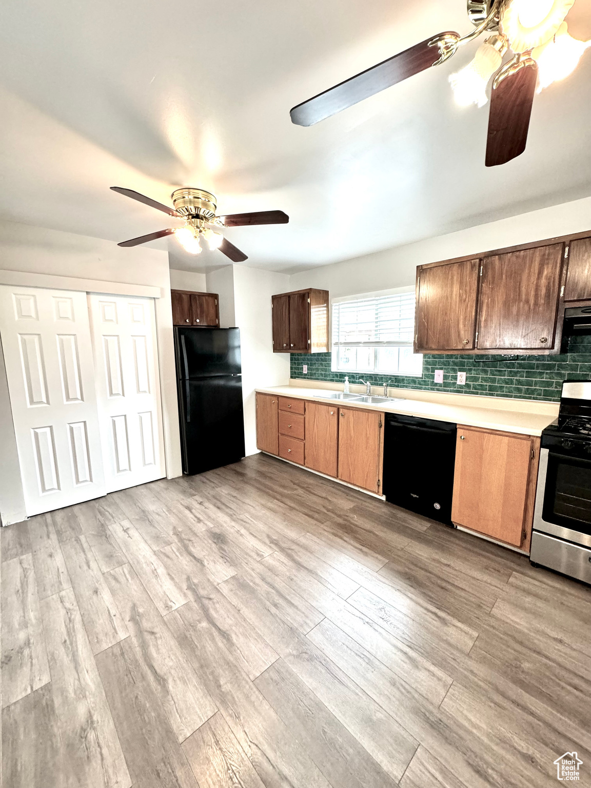 Kitchen with light hardwood / wood-style flooring, black appliances, sink, tasteful backsplash, and ceiling fan
