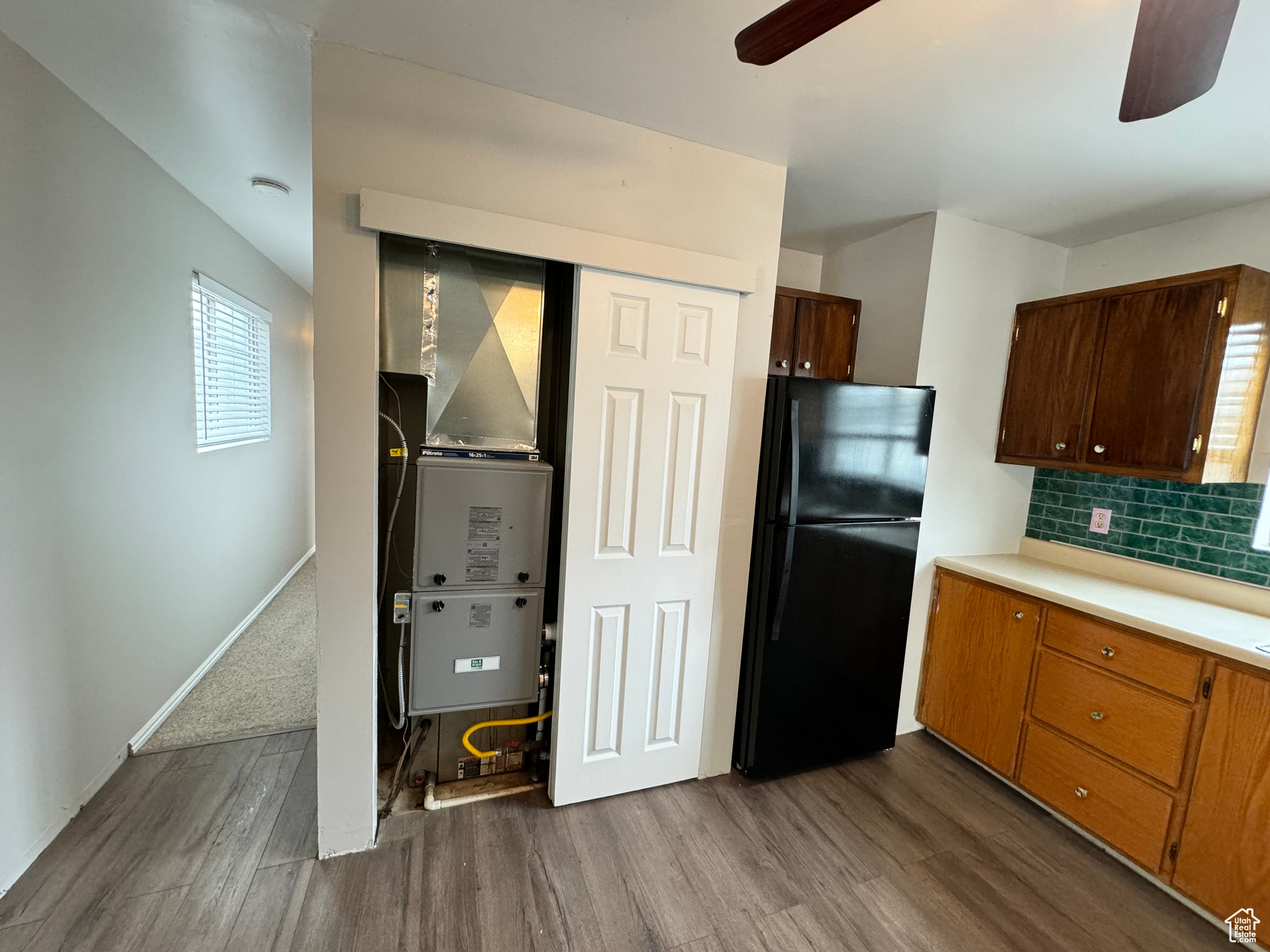 Kitchen with black refrigerator, ceiling fan, tasteful backsplash, and wood-type flooring