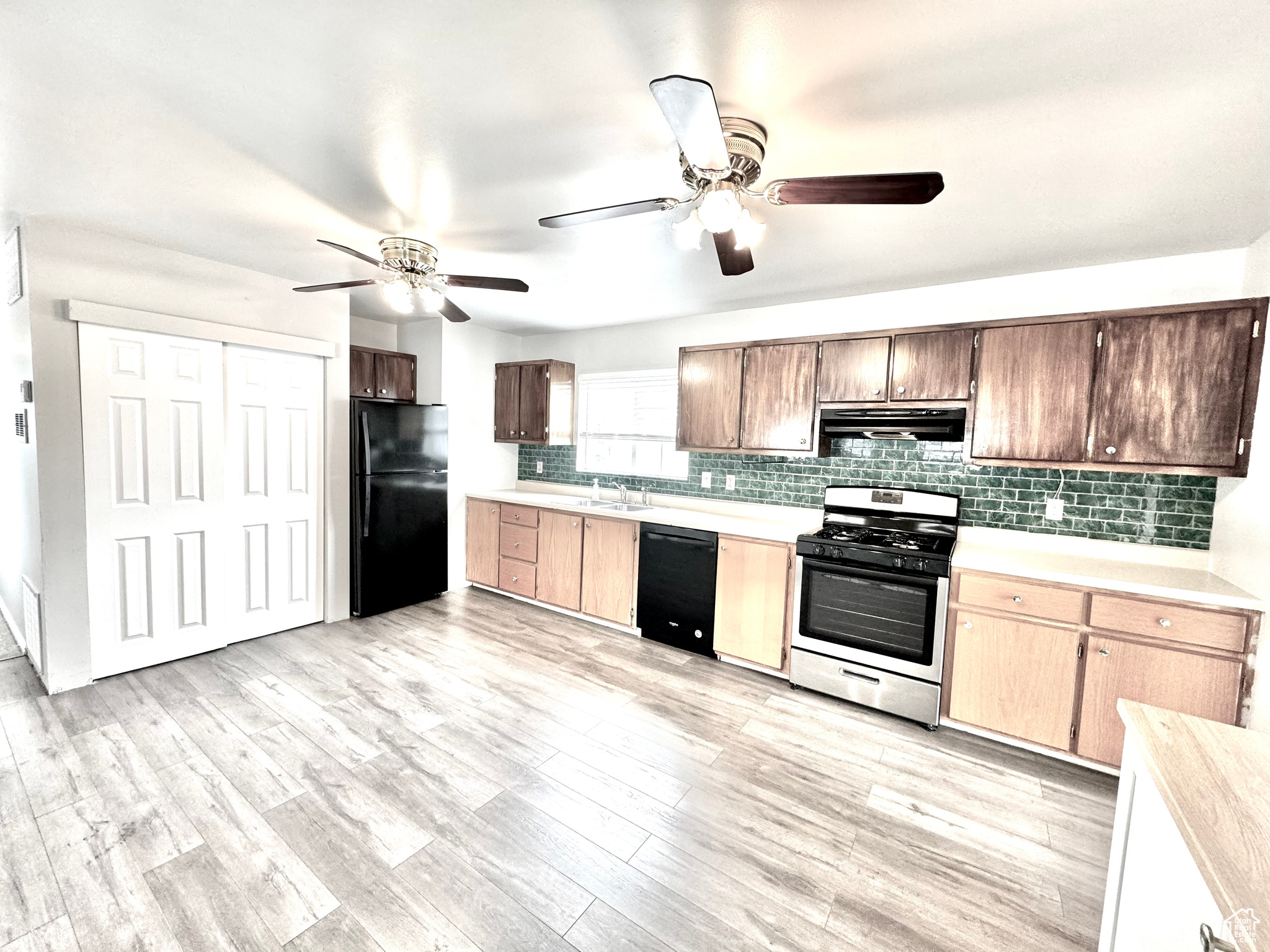 Kitchen featuring tasteful backsplash, light hardwood / wood-style flooring, ceiling fan, and black appliances