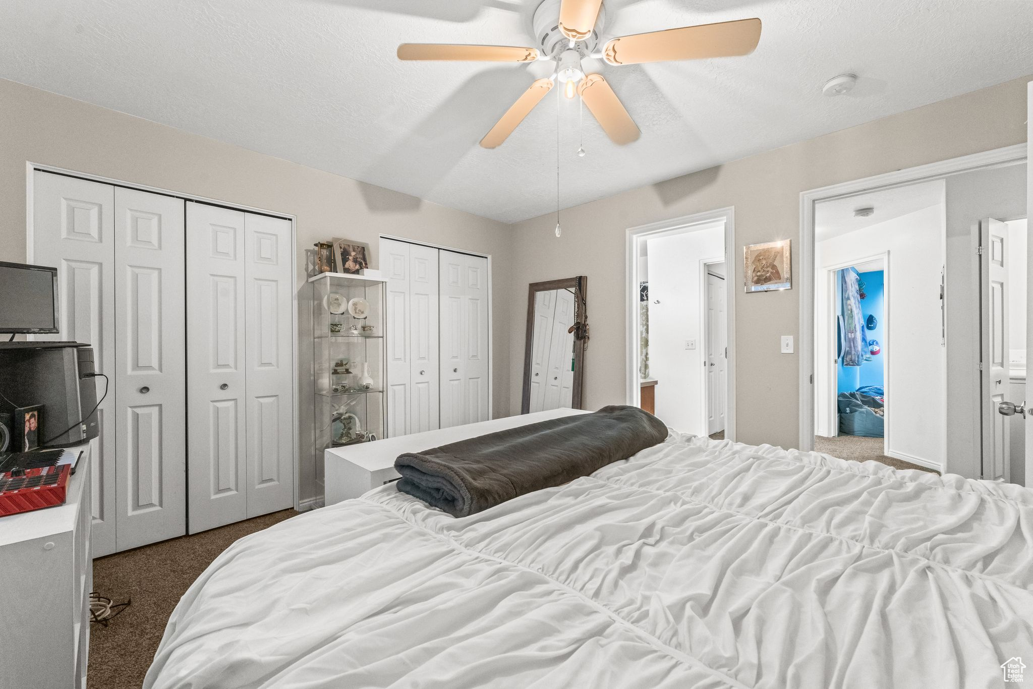 Carpeted bedroom with ceiling fan and two closets