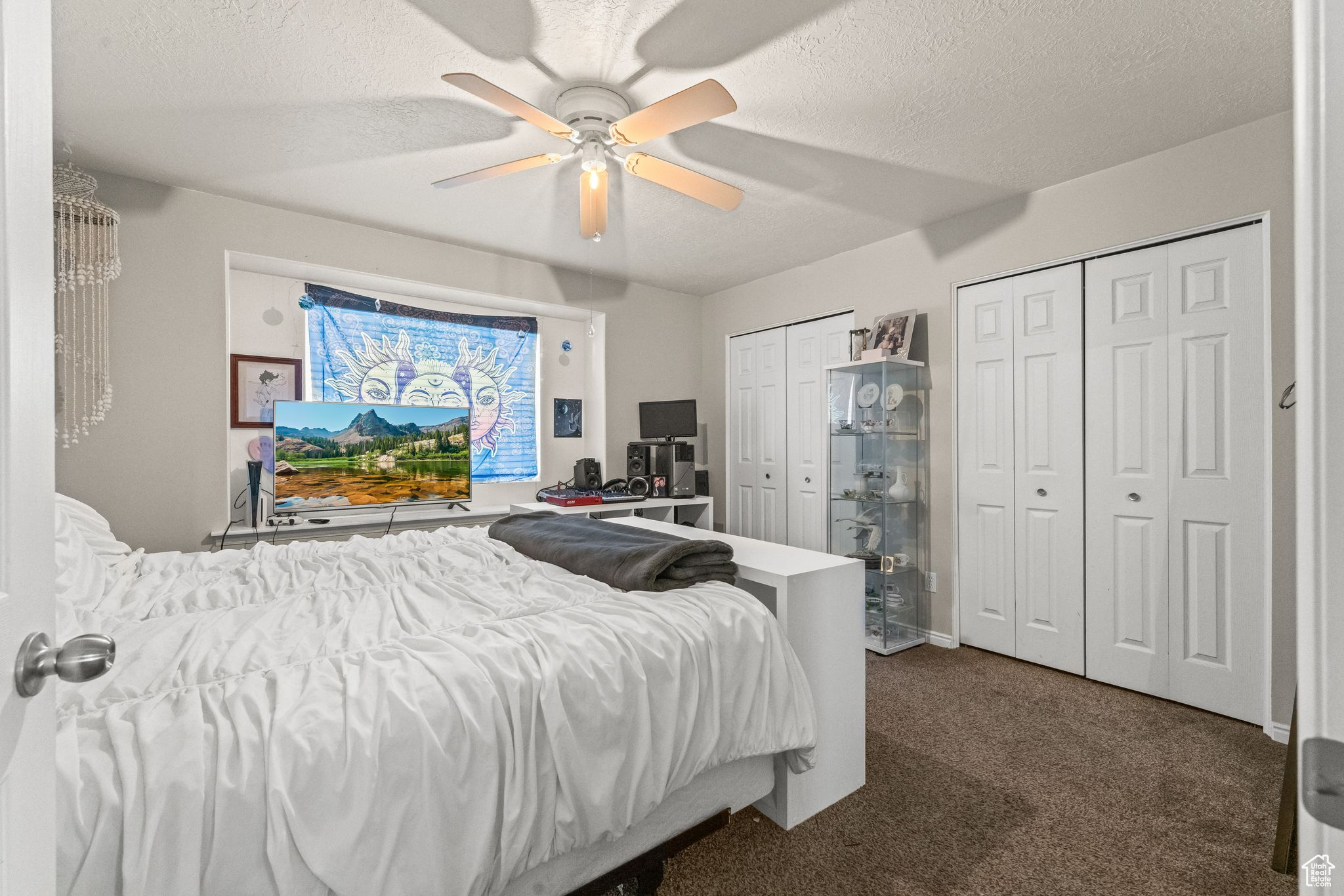 Carpeted bedroom with multiple closets, a textured ceiling, and ceiling fan