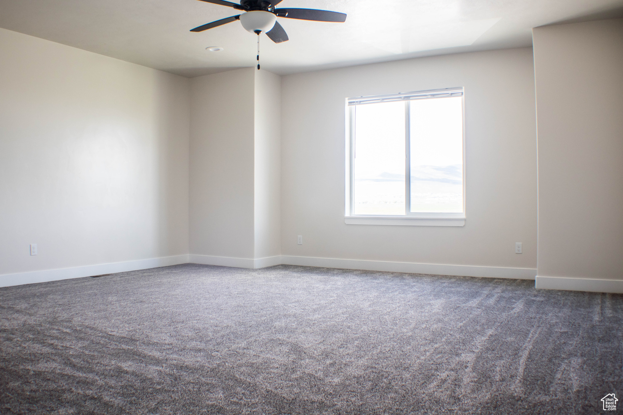 Empty room with ceiling fan and carpet flooring