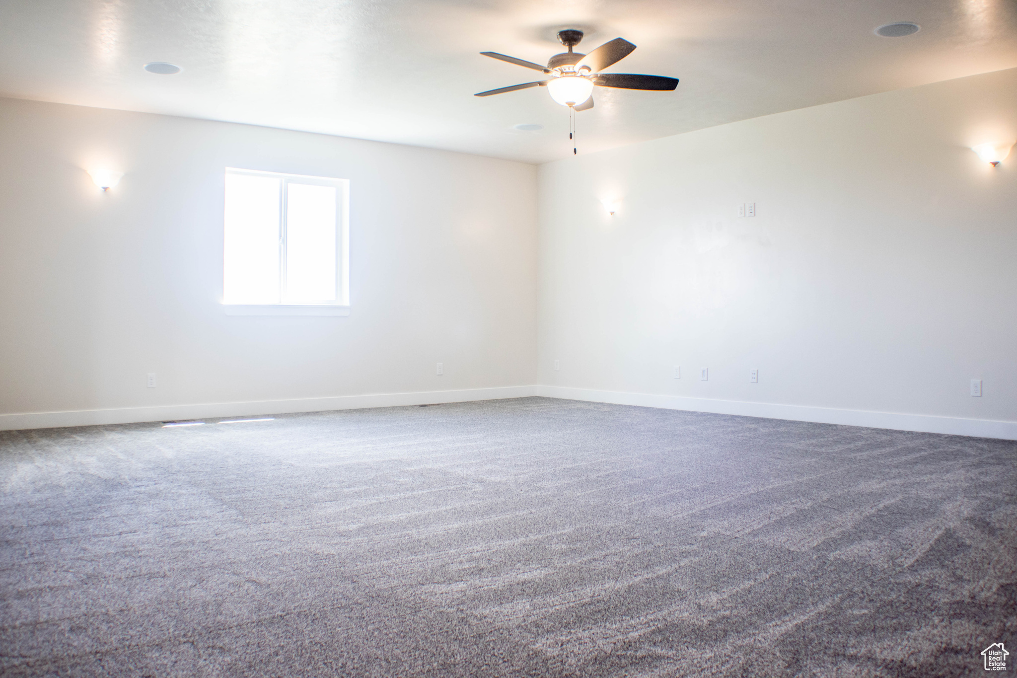 Spacious carpeted family entertainment room featuring ceiling fan