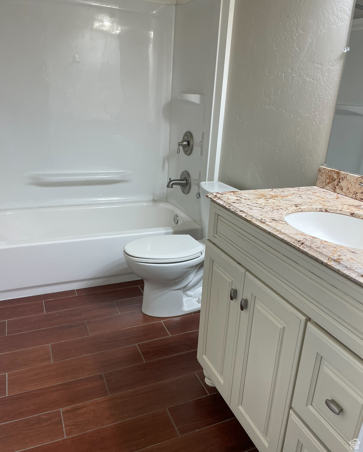 Full bathroom with vanity, toilet, shower / tub combination, and hardwood / wood-style floors