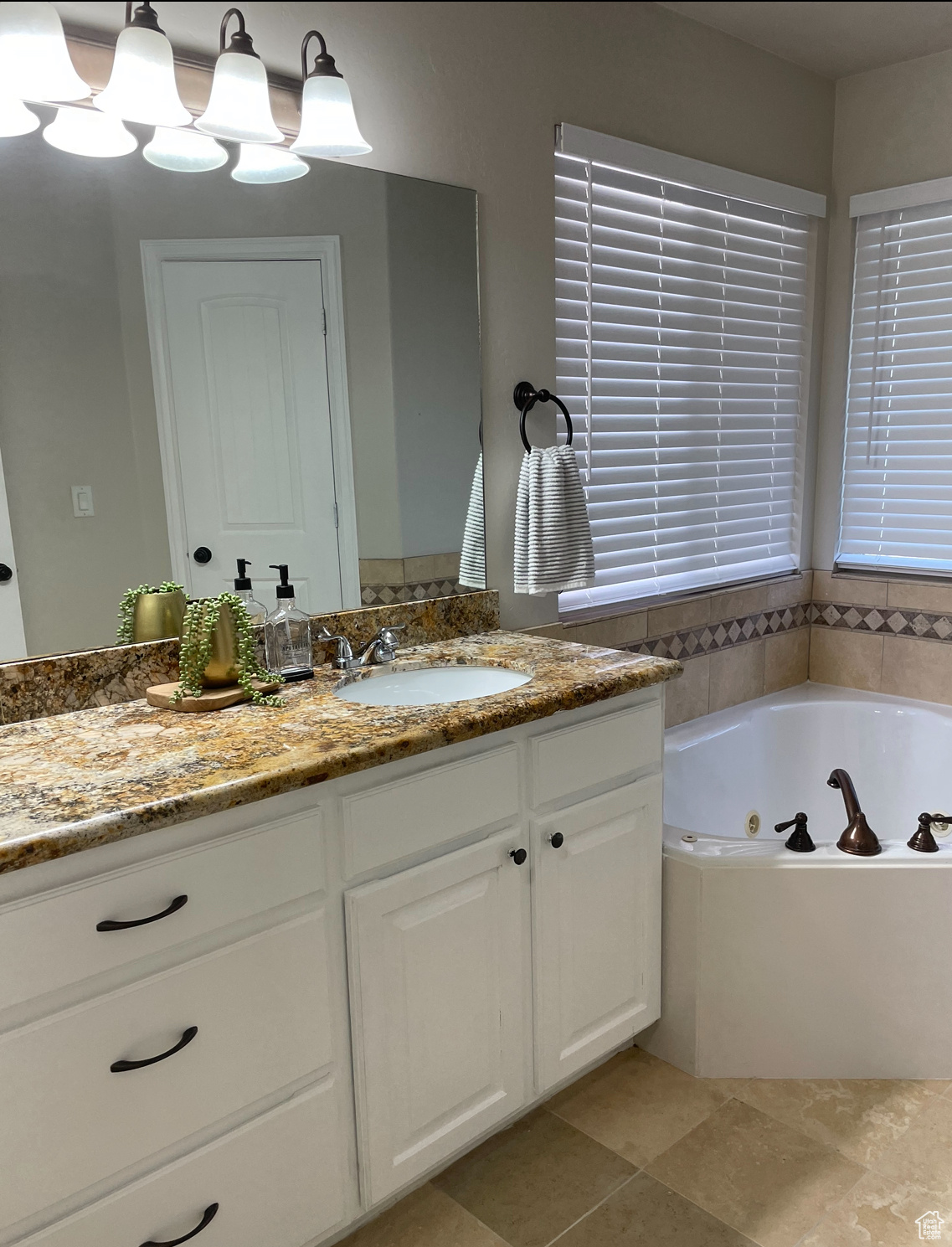 Bathroom with tile patterned floors, vanity, and a washtub