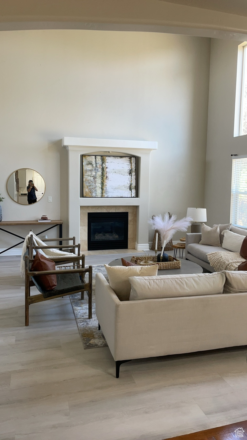 Living room with a fireplace, a towering ceiling, and light hardwood / wood-style flooring