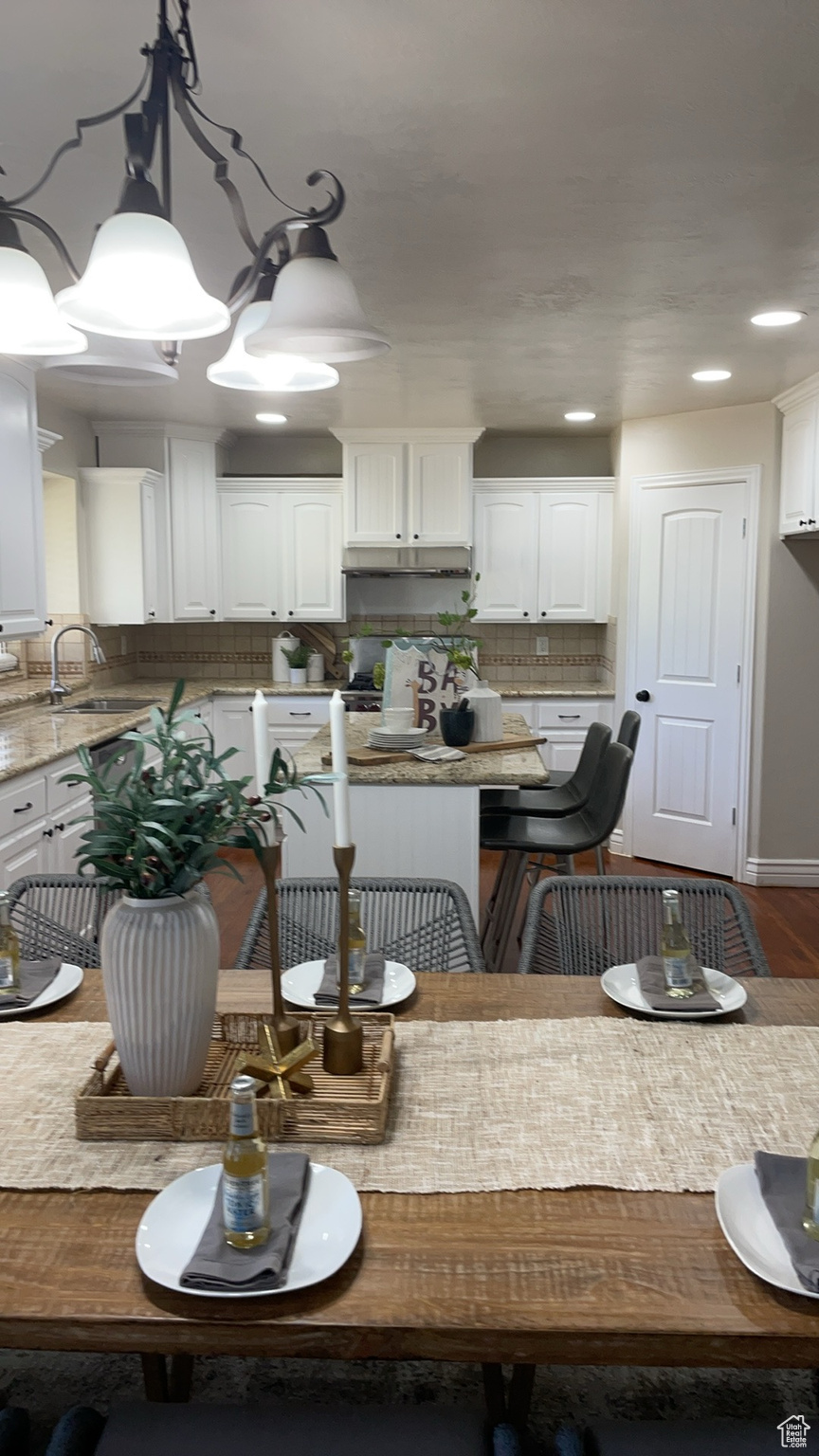 Kitchen with hardwood / wood-style floors, sink, pendant lighting, backsplash, and white cabinetry