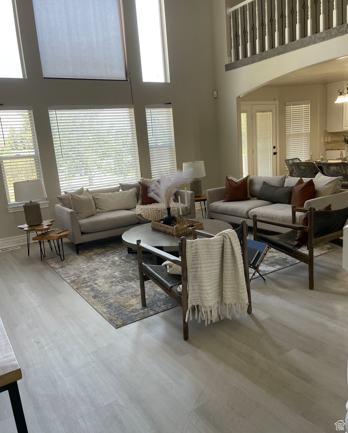 Living room with wood-type flooring, a wealth of natural light, and a towering ceiling