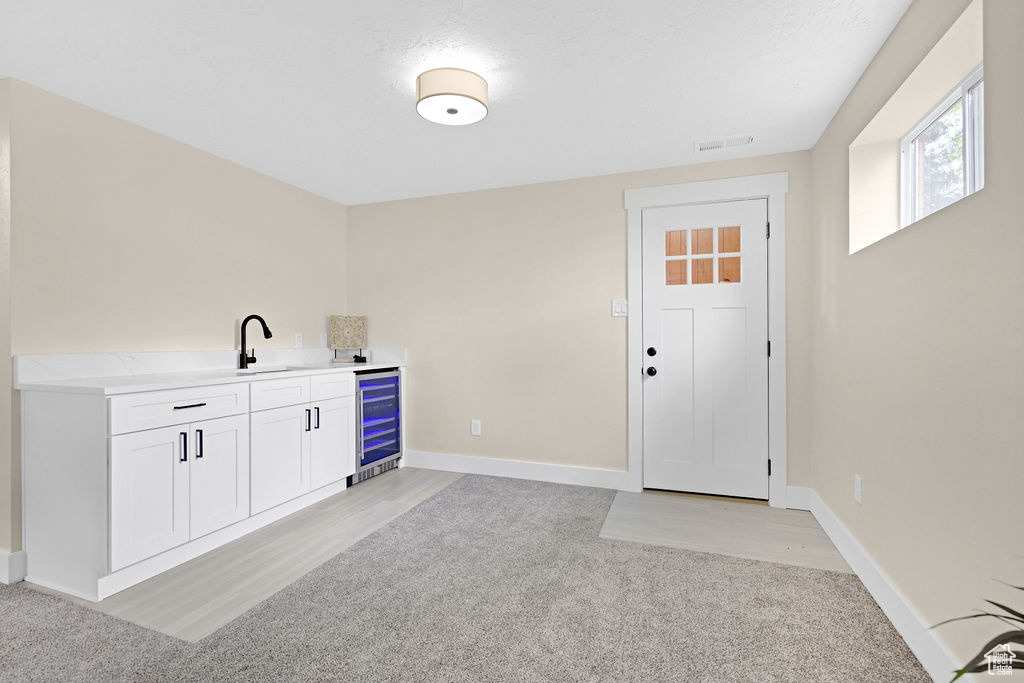 Interior space with light colored carpet, white cabinets, and beverage cooler