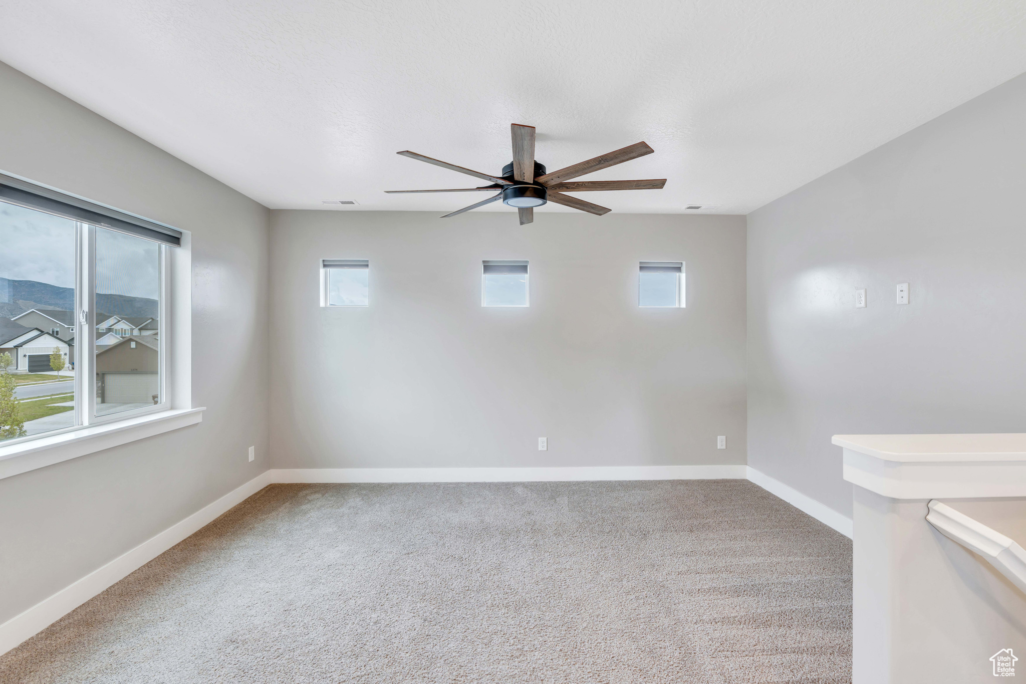 Carpeted loft featuring a wealth of natural light and ceiling fan