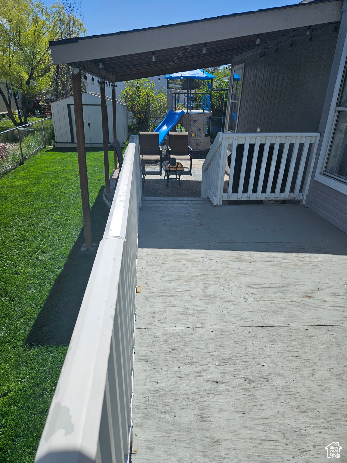 View of patio with a playground and a storage shed