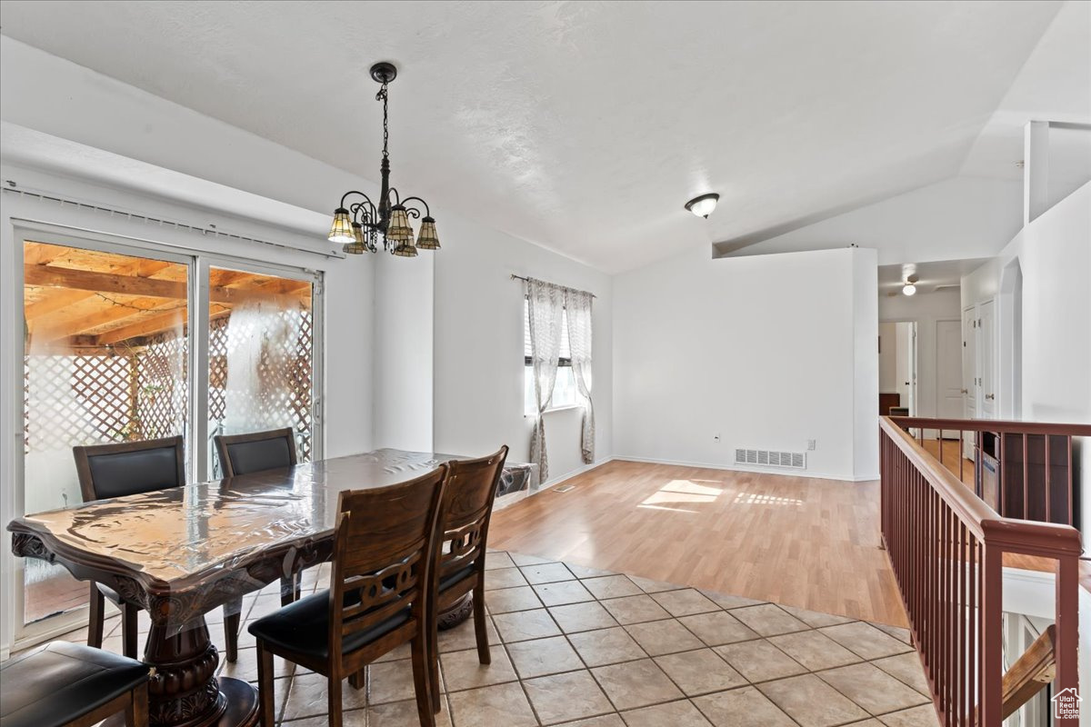 Dining space with vaulted ceiling, light hardwood / wood-style flooring, and a notable chandelier