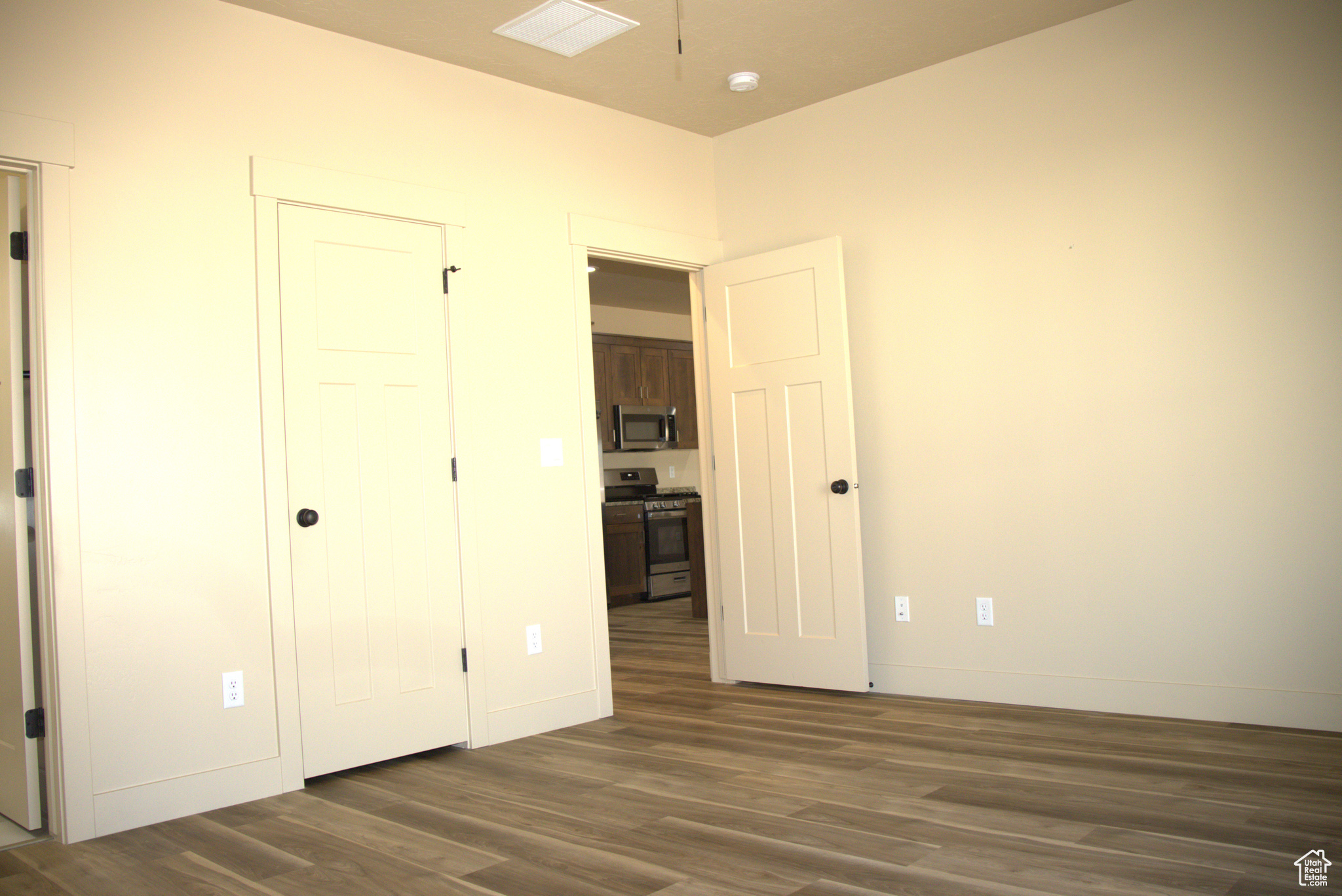 Unfurnished bedroom featuring dark hardwood / wood-style flooring, master bath, walk-in closet