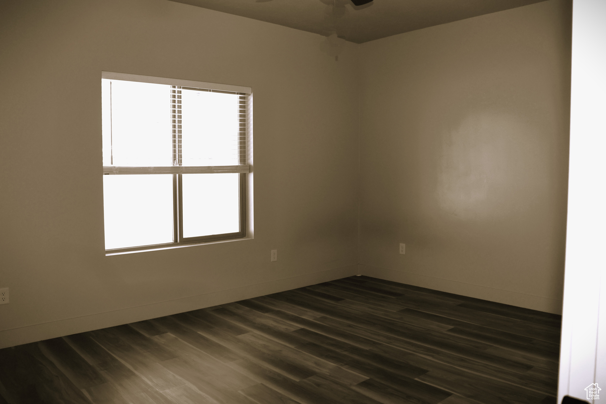 Empty room featuring plenty of natural light, ceiling fan, and dark hardwood / wood-style floors