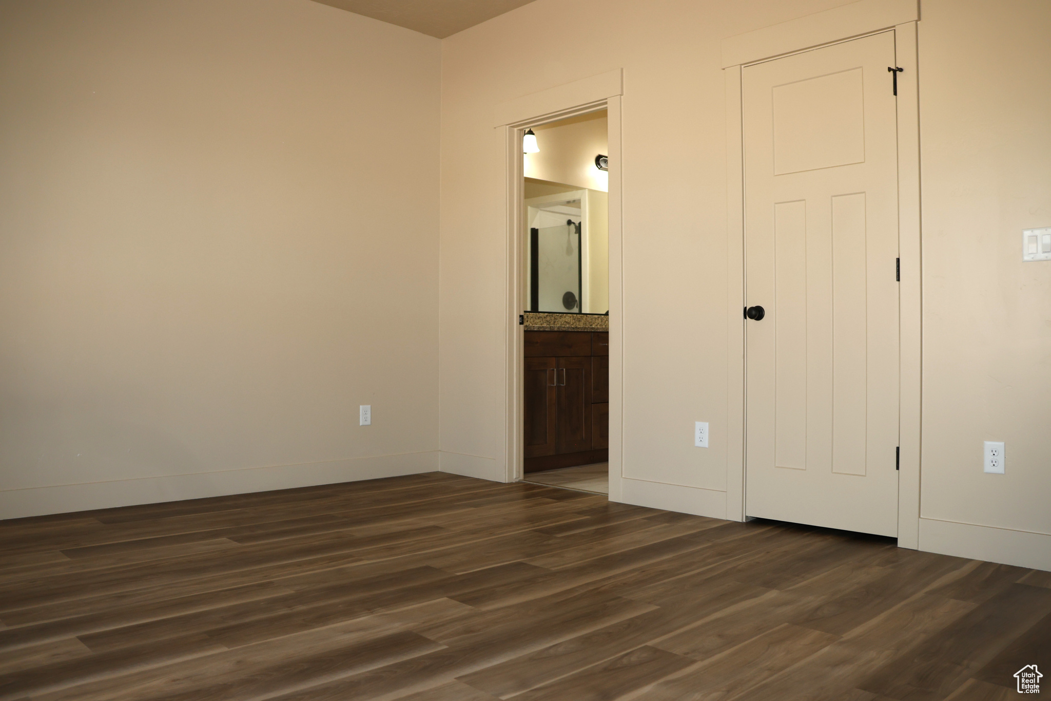 Unfurnished bedroom featuring dark wood-type flooring and ensuite bathroom