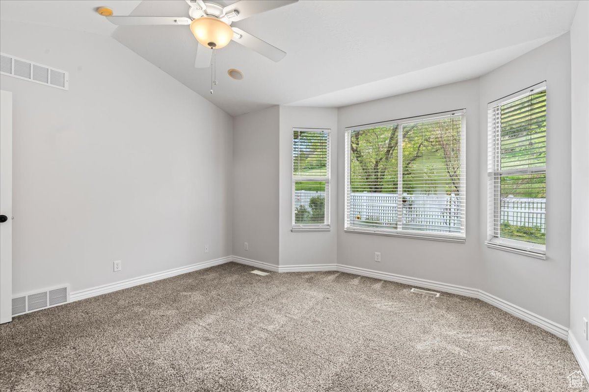 Empty room featuring ceiling fan, carpet floors, and plenty of natural light