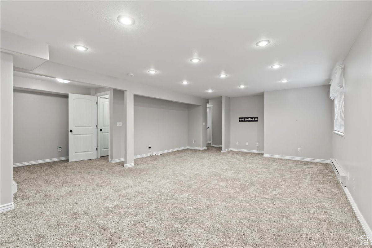Basement featuring light carpet and a baseboard heating unit